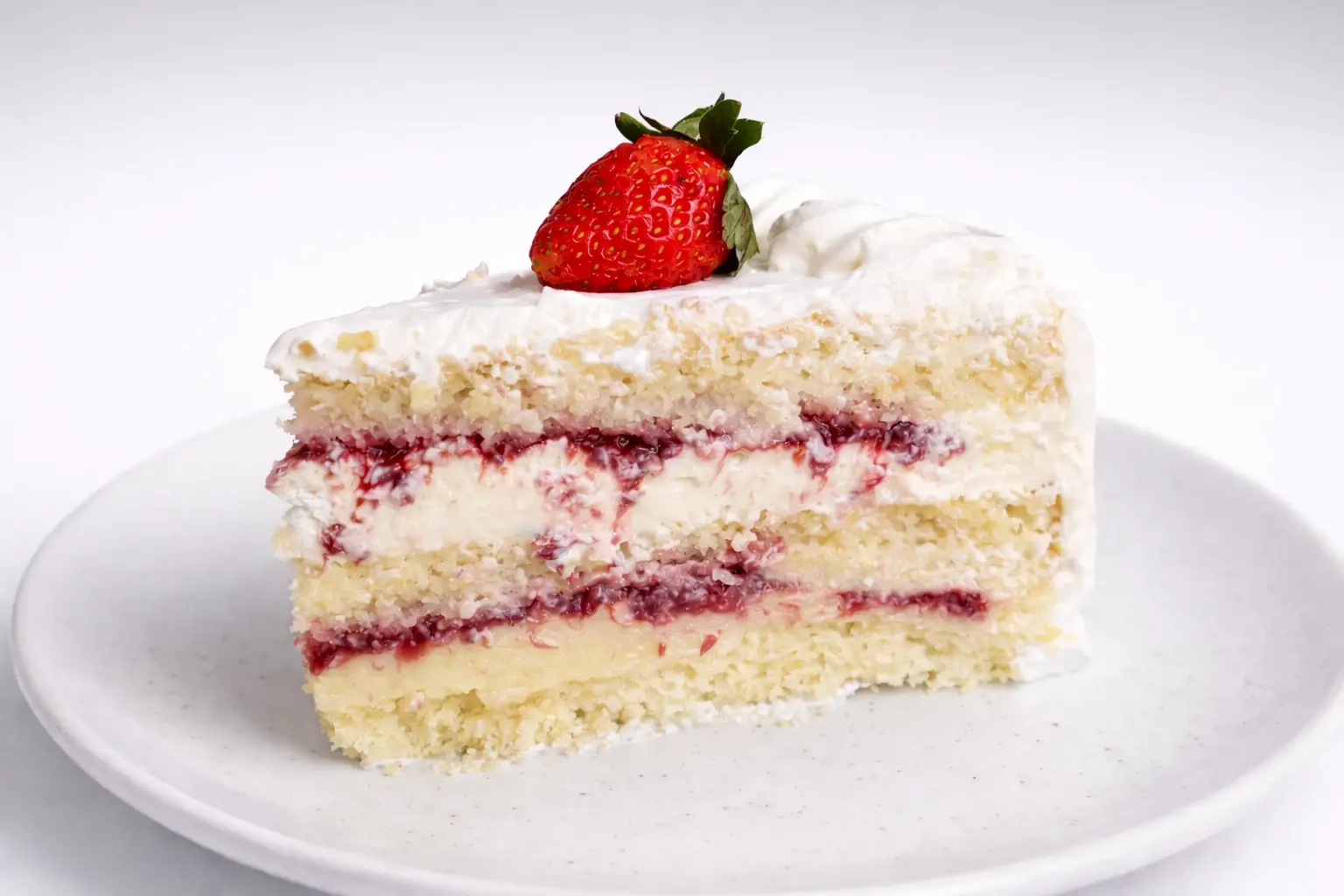 Fatia de bolo de morango com chantilly sobre prato branco
